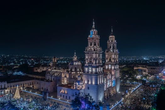 Nighttime aerial view of the illuminated Morelia Cathedral in Mexico, with vibrant city lights.