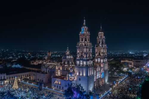 Free Nighttime aerial view of the illuminated Morelia Cathedral in Mexico, with vibrant city lights. Stock Photo