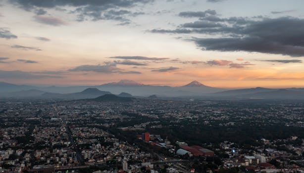 A stunning aerial view of a city with mountains in the background at sunset.