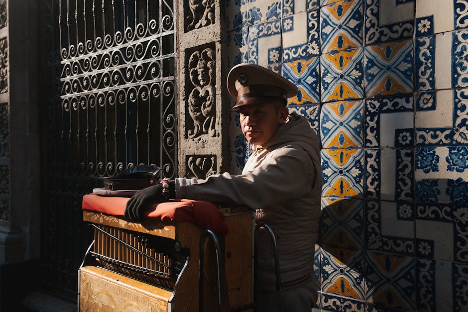 Organ grinder performing in a Mexican street with traditional attire and ornate tiled backdrop. in Tulum