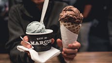 特写镜头里，手里拿着巧克力蛋卷和独特风味冰淇淋杯