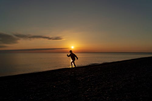Silhouette of Man Walking on the Shore