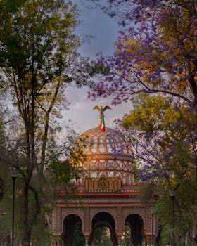 The Morisco Kiosk in Mexico City's Alameda Park framed by lush trees under a warm daylight.