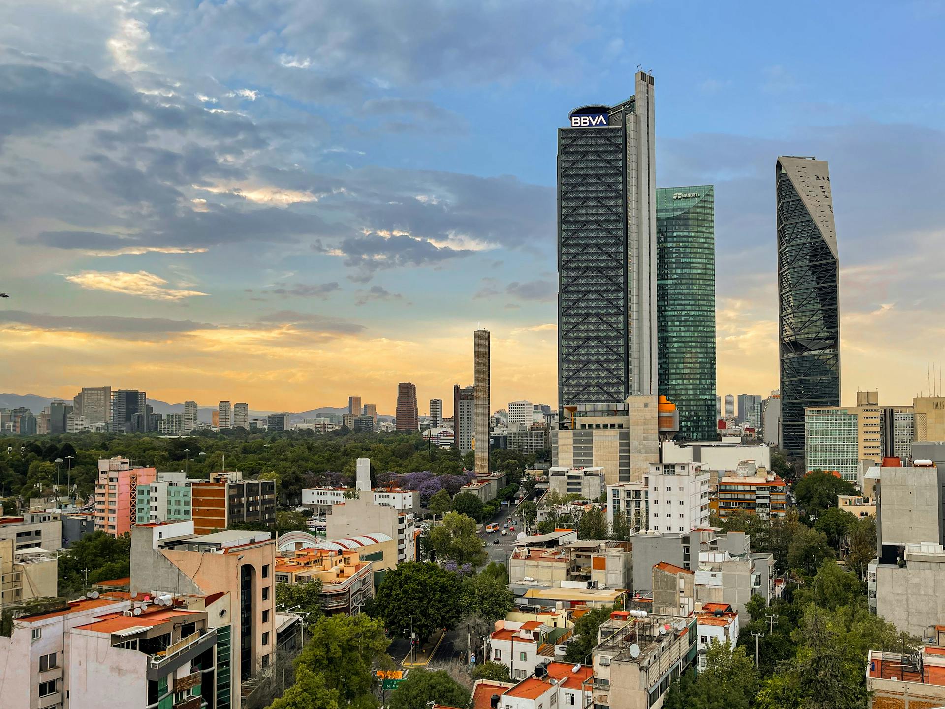 Panoramic view of Mexico City's modern skyline at sunset, highlighting iconic BBVA tower.