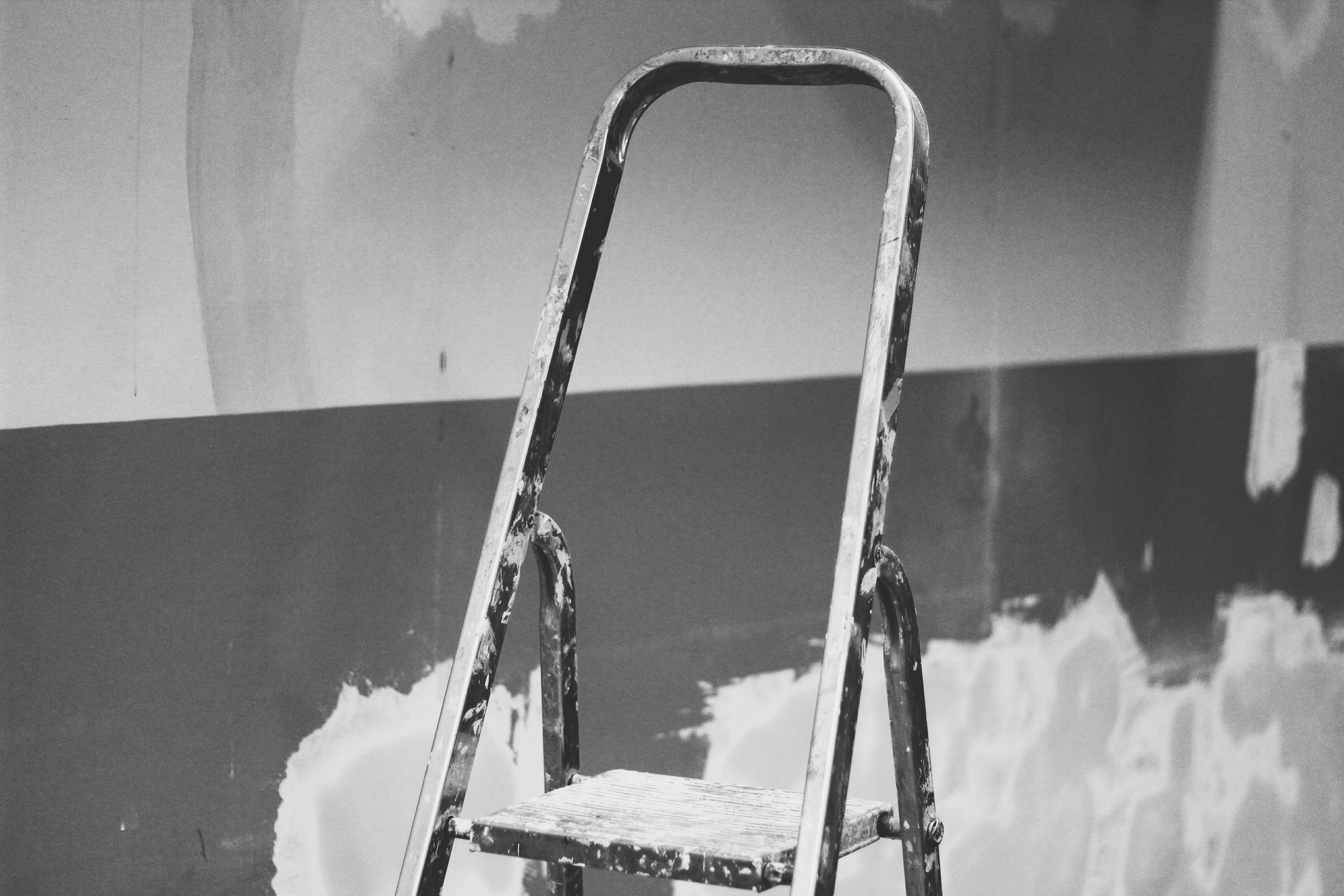 black and gray step ladder in front of wall