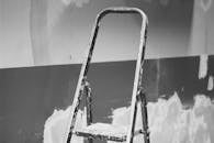 一把旧梯子靠在彩绘纹理墙上的黑白照片