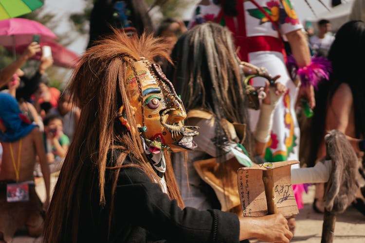 Close Up Of A Person In A Carnival Mask And Crowd In Background