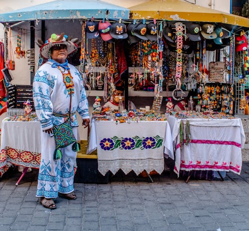 Man in Traditional Clothing in Front of a Market Stall 