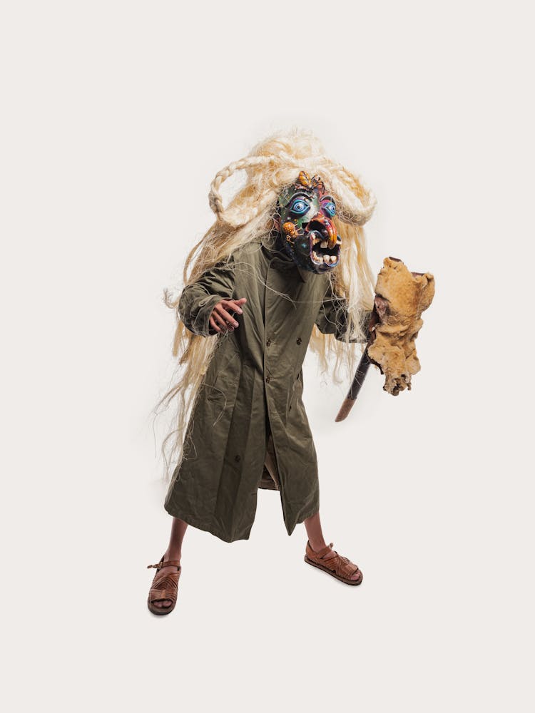 Studio Shot Of A Man In A Coat And Carnival Mask With A Stick