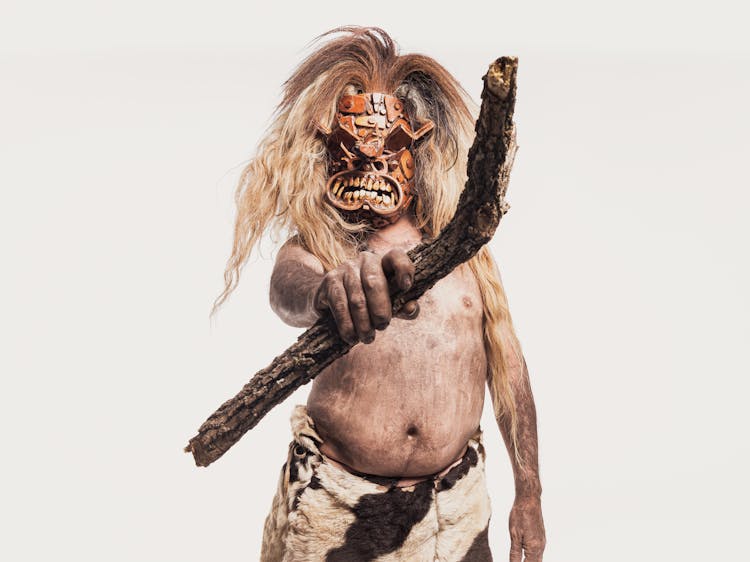 Studio Shot Of A Man In A Leather Carnival Costume And Carnival Mask Holding A Stick