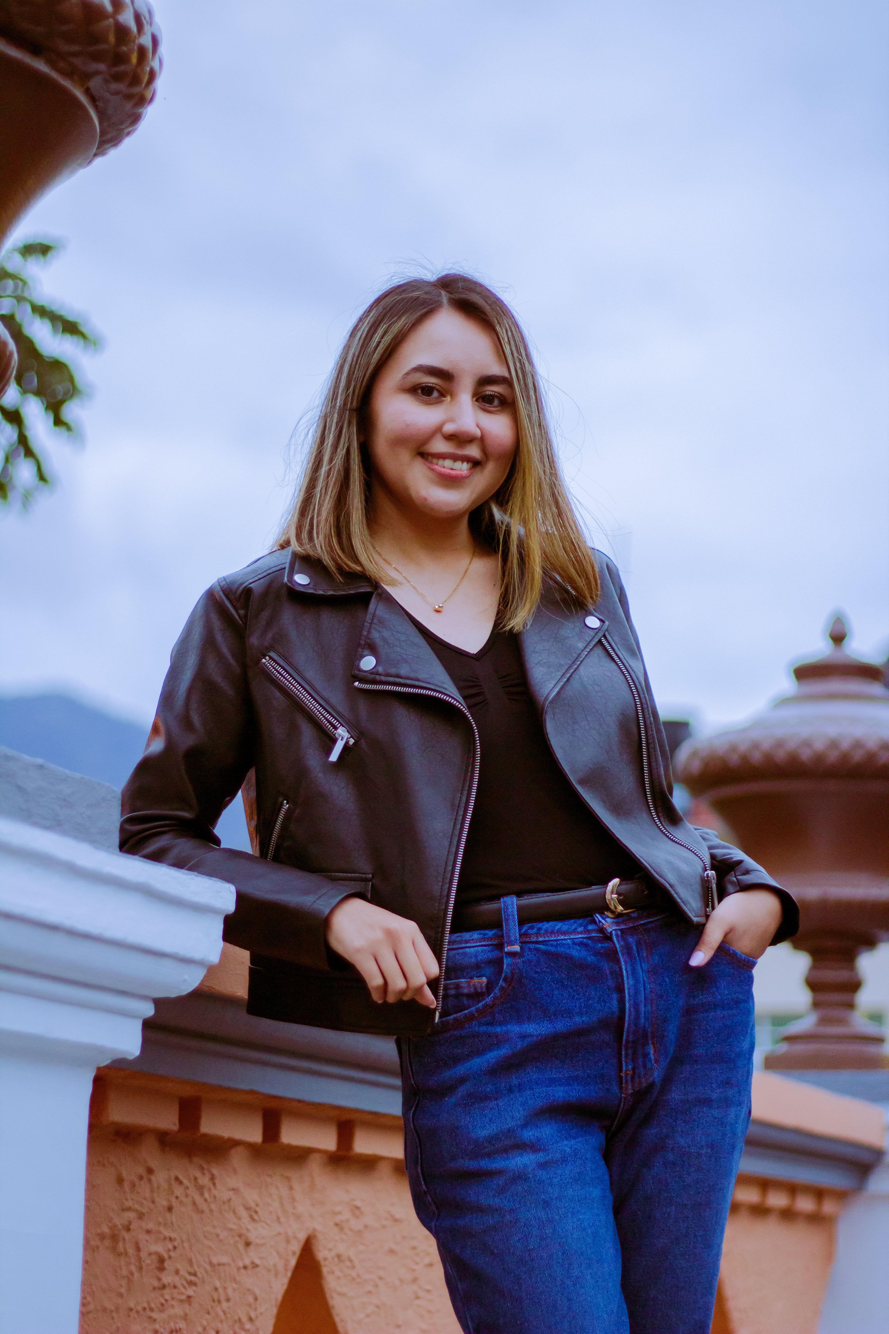 Smiling Woman in Black Leather Jacket Posing Beside a Railing · Free ...