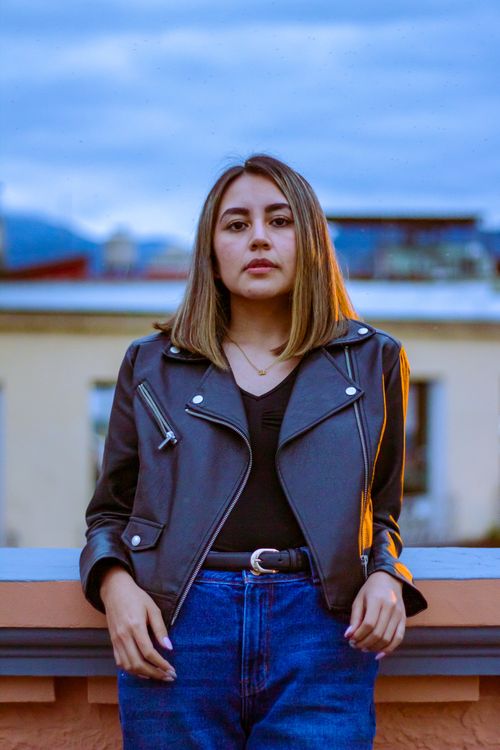 Smiling Woman in Black Leather Jacket Posing Beside a Railing · Free ...