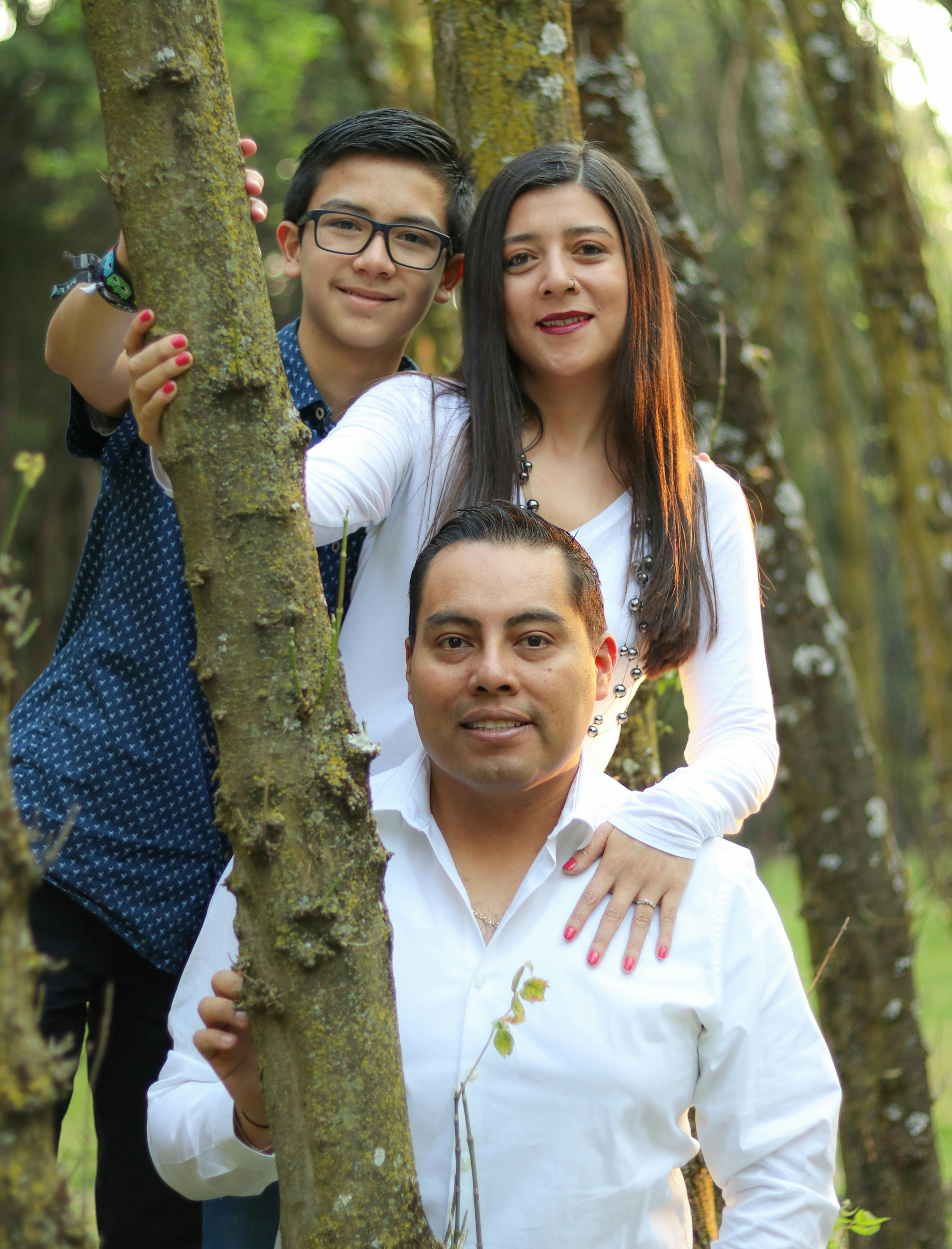 A joyful family portrait in a forest setting, featuring parents and their teenage son.