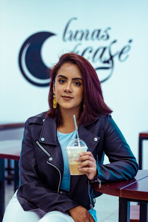 Young Woman Sitting with a Drink in a Disposable Cup