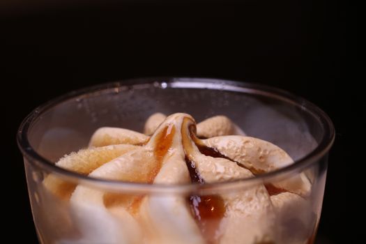 Close-up of a delicious ice cream dessert topped with caramel syrup in a glass.