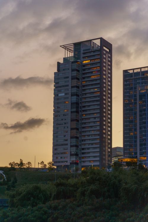 Free A contemporary high-rise building against a sunset sky, featuring urban architecture. Stock Photo
