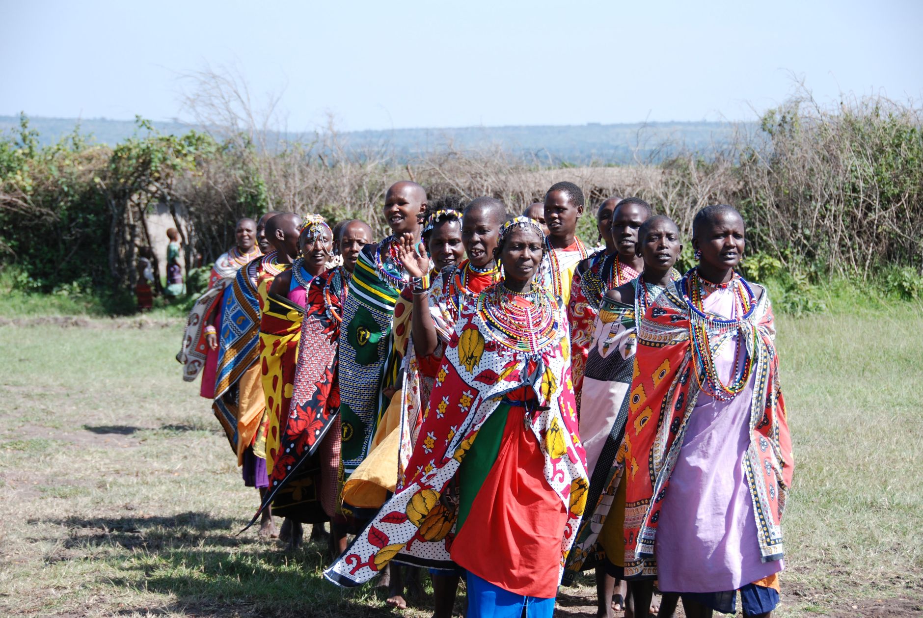Group of Maasai women wearing traditional attire in a rural outdoor setting.
