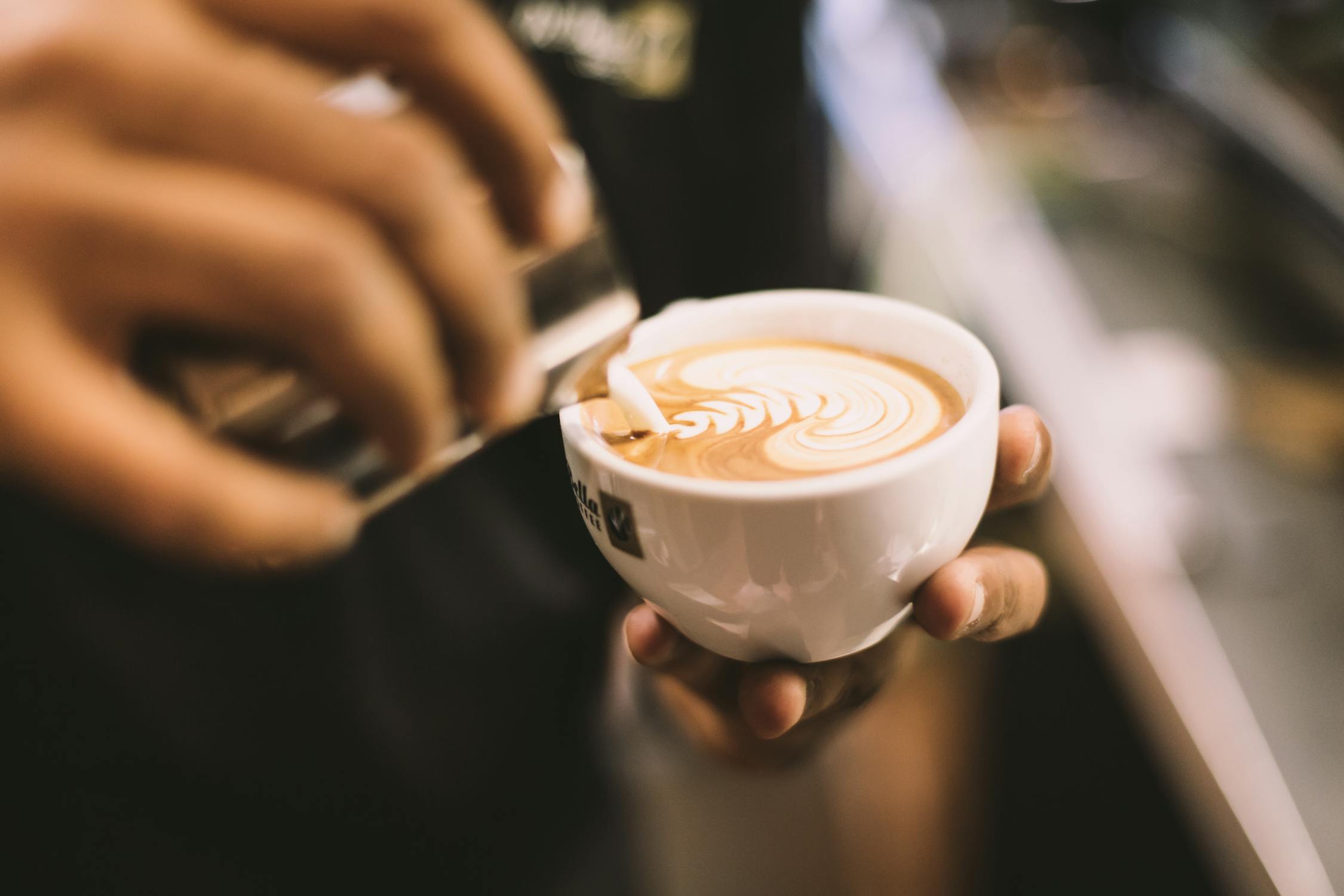 Image of person holding white ceramic mug filled with cappuccino