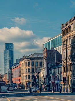 Vibrant street view of Manchester showcasing historic and modern architecture under a sunny sky.