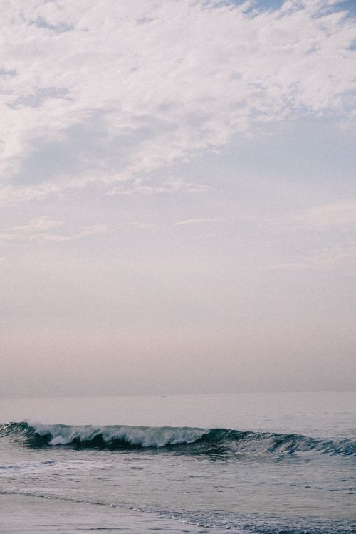 Free Tranquil waves on a calm sea with a cloudy sky in a serene setting. Stock Photo