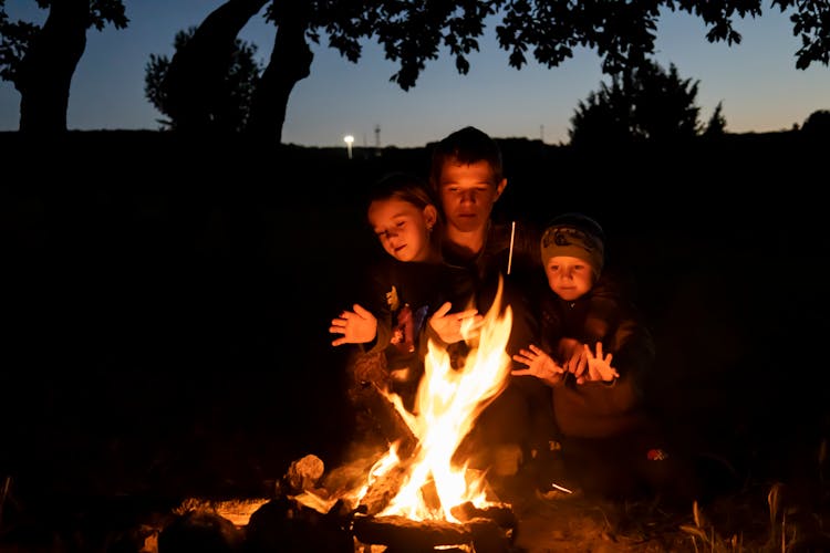 Father And Kids Sitting Beside A Campfire