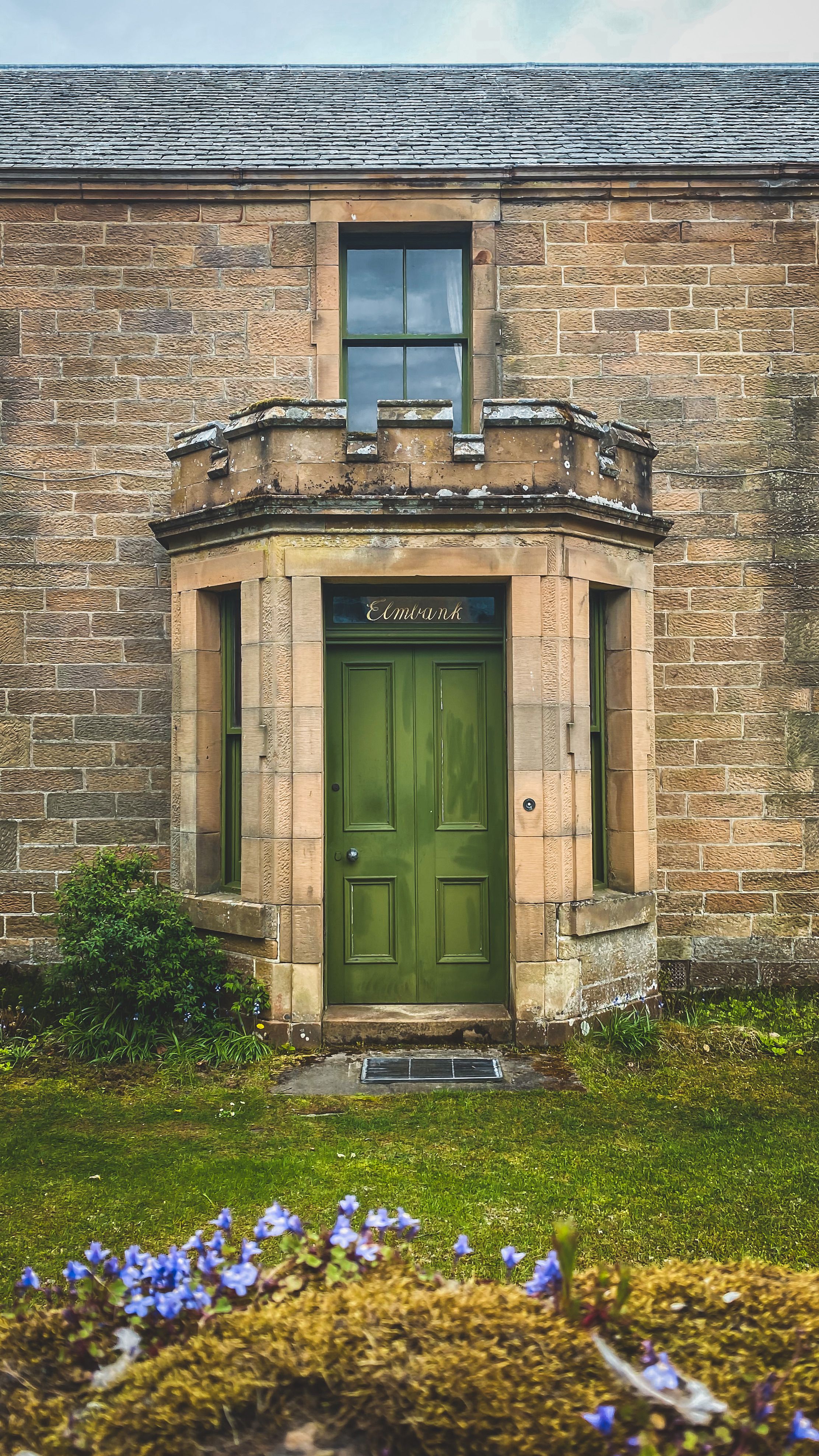 Charming sandstone house with a green door in Dornoch, Scotland. Perfect for architectural themes.