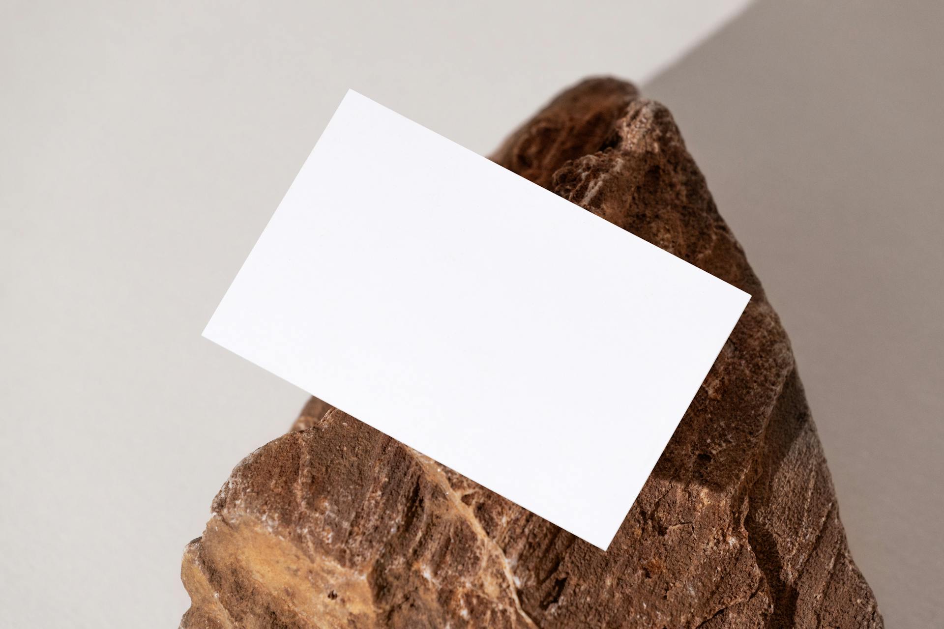 Minimalist mockup of a blank business card placed on a textured rock surface, offering versatile copy space.
