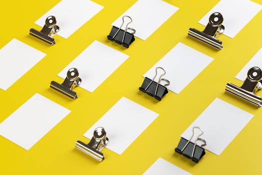 Flat lay of paper clips and sheets on yellow, ideal for business and creativity themes.
