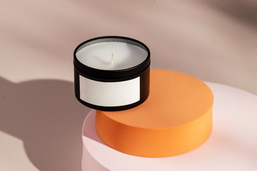Stylish black candle on pastel geometric stands with blank label, perfect for branding concepts.