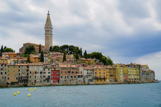 Charming view of Rovinj's colorful waterfront and iconic bell tower on a cloudy day.