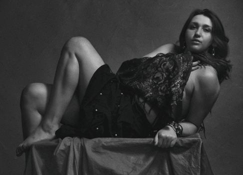 Artistic black and white studio portrait of a fashionable woman posing with elegance.