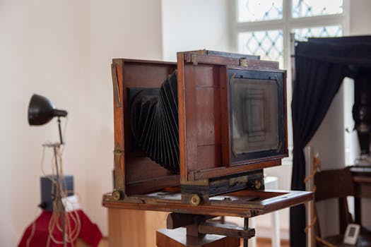 Close-up of a classic wooden box camera in a vintage studio environment.