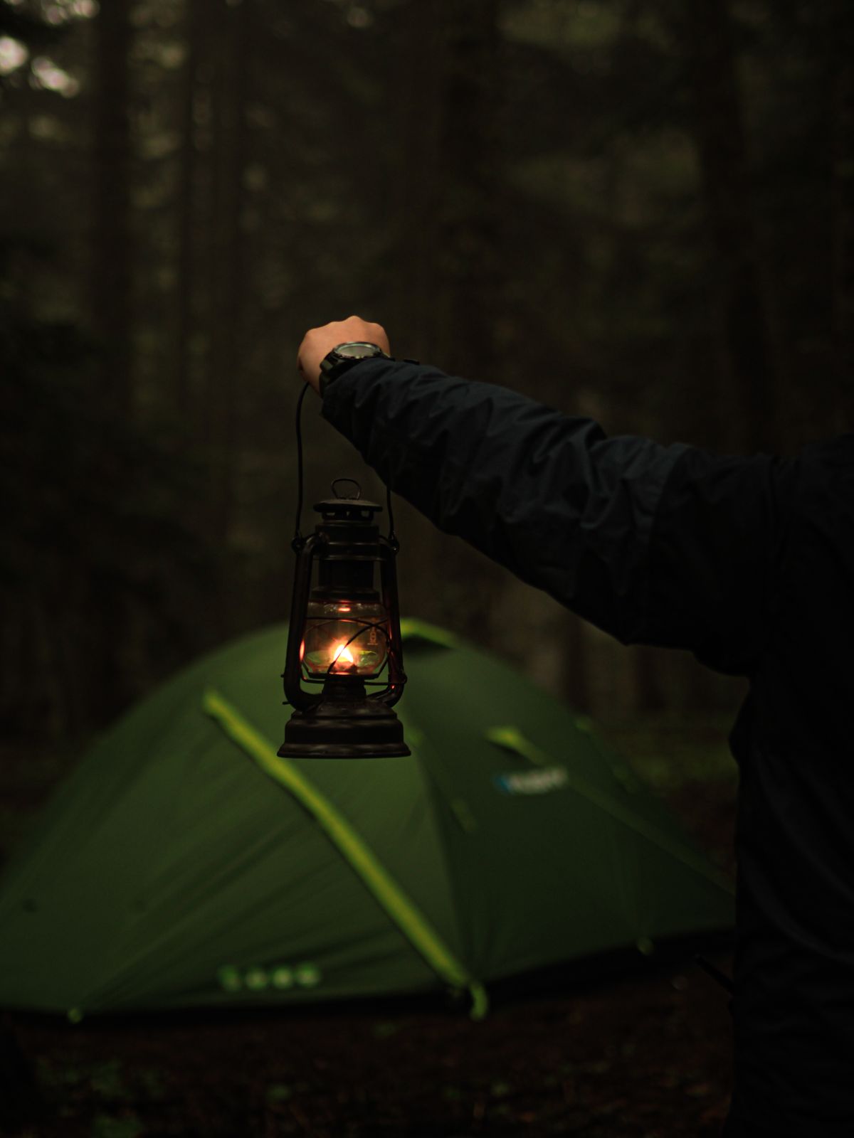 Camper using a lantern at a tent after dark