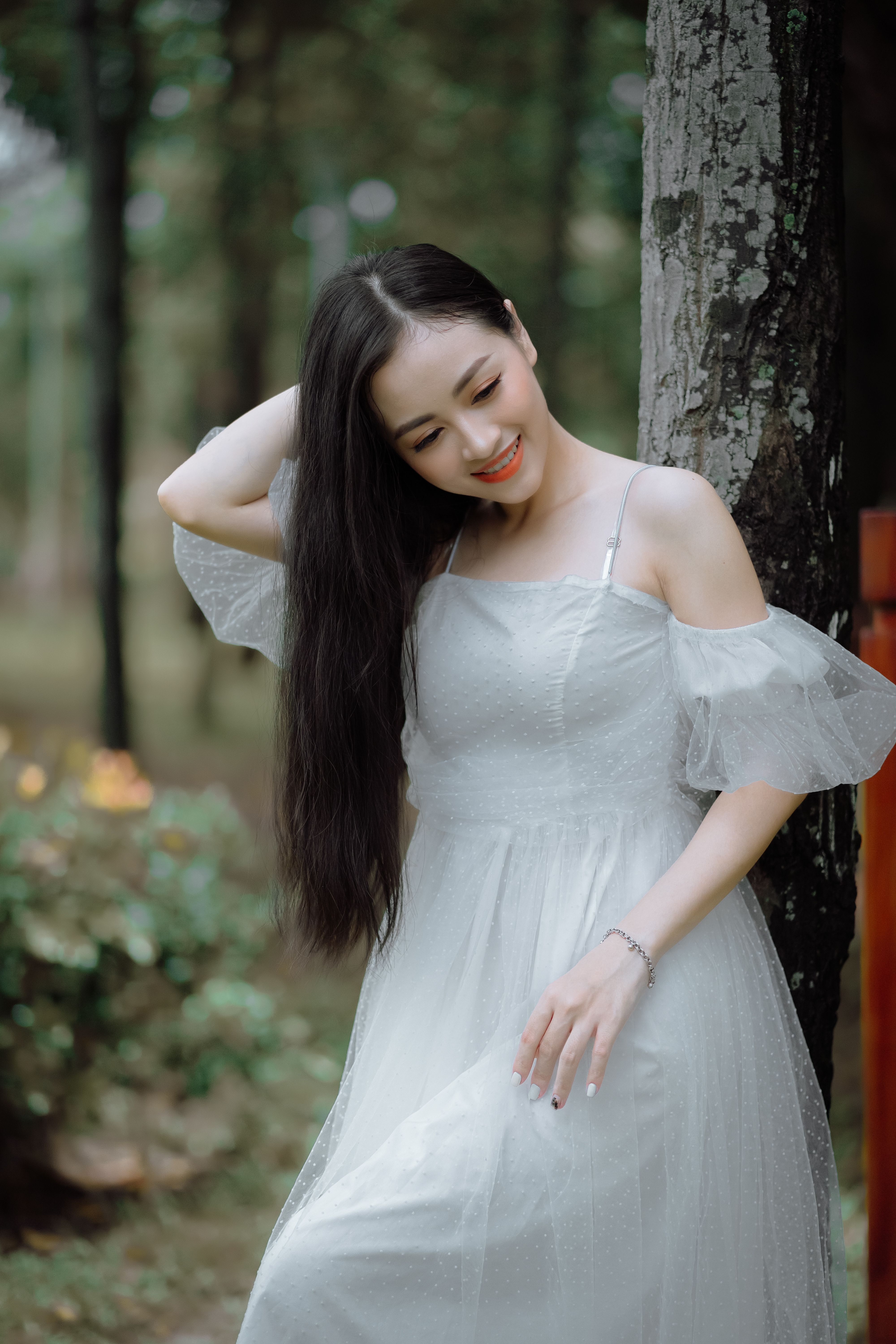 A Woman in Gray Dress Standing Beside Tree Trunk · Free Stock Photo