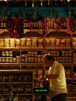 Man weighing products in an organic shop surrounded by diverse packages and jars.