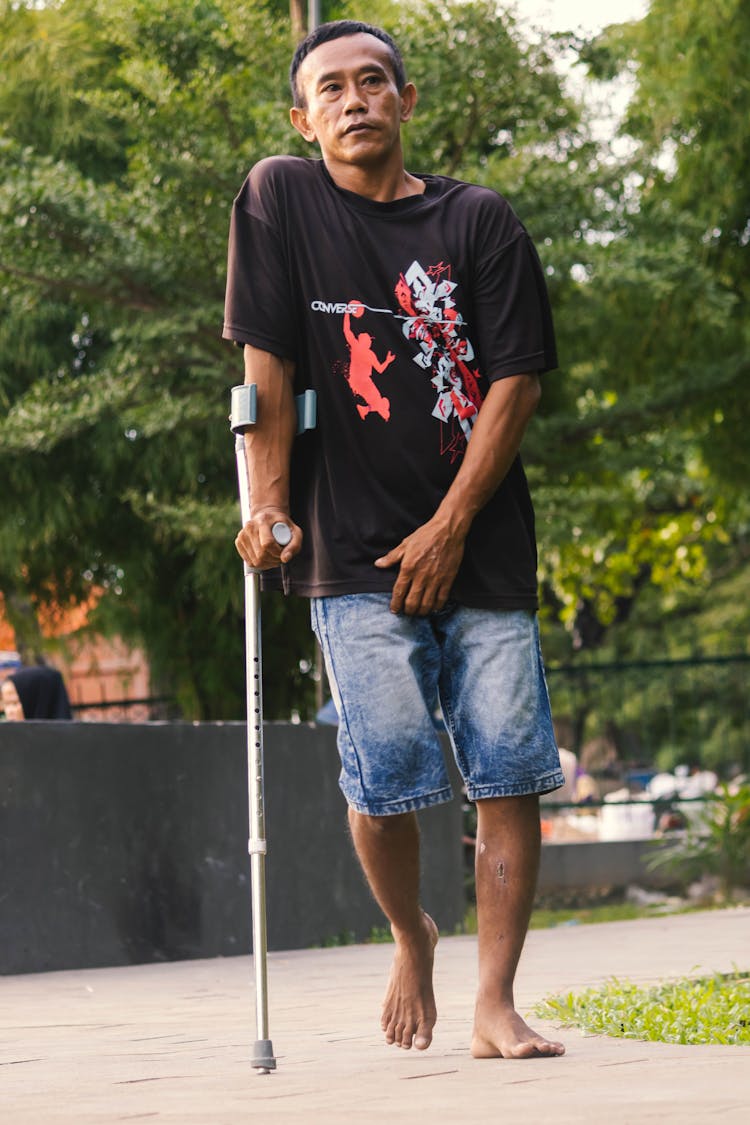 Man Walking With A Crutch 