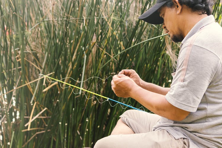 Man Tying Wire Over Fishing Rod