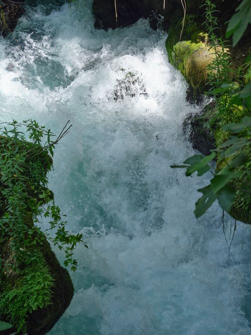 Free A dramatic aerial shot of a vibrant waterfall rushing through lush green foliage. Stock Photo
