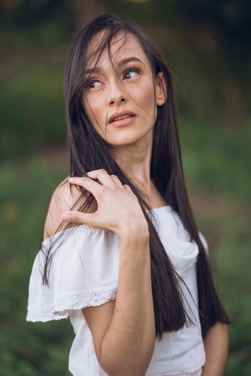 Woman with Long Hair in a White Blouse Looking over Shoulder
