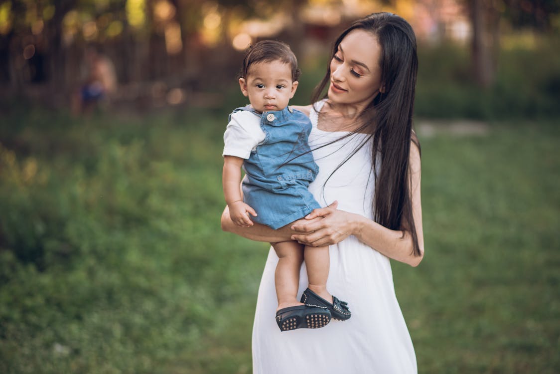 A Woman in White Dress Carrying Her Child