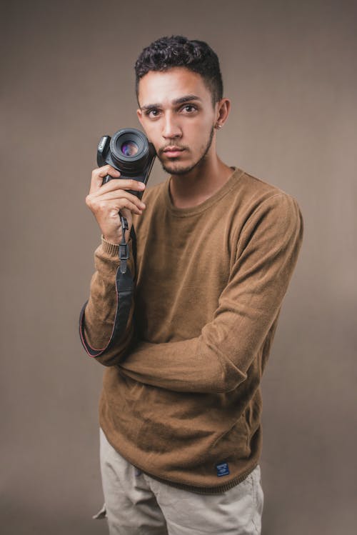 Foto profissional grátis de blusa marrom, câmera, de pé