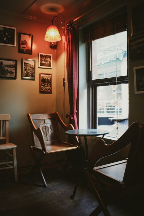 Free Warm and inviting cafe corner featuring vintage wooden chairs and ambient lighting. Stock Photo