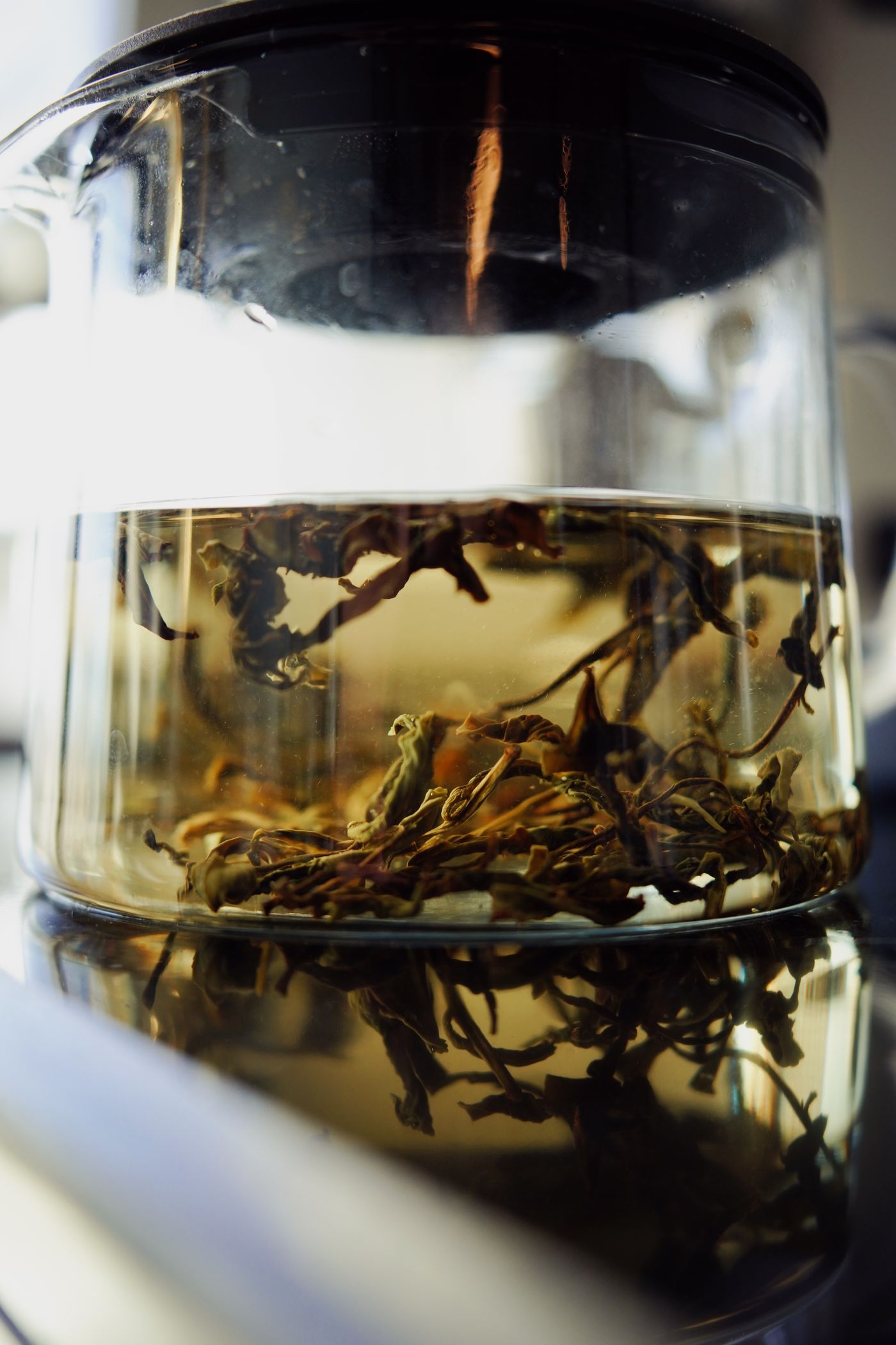 Loose-leaf tea steeping in a clear glass teapot
