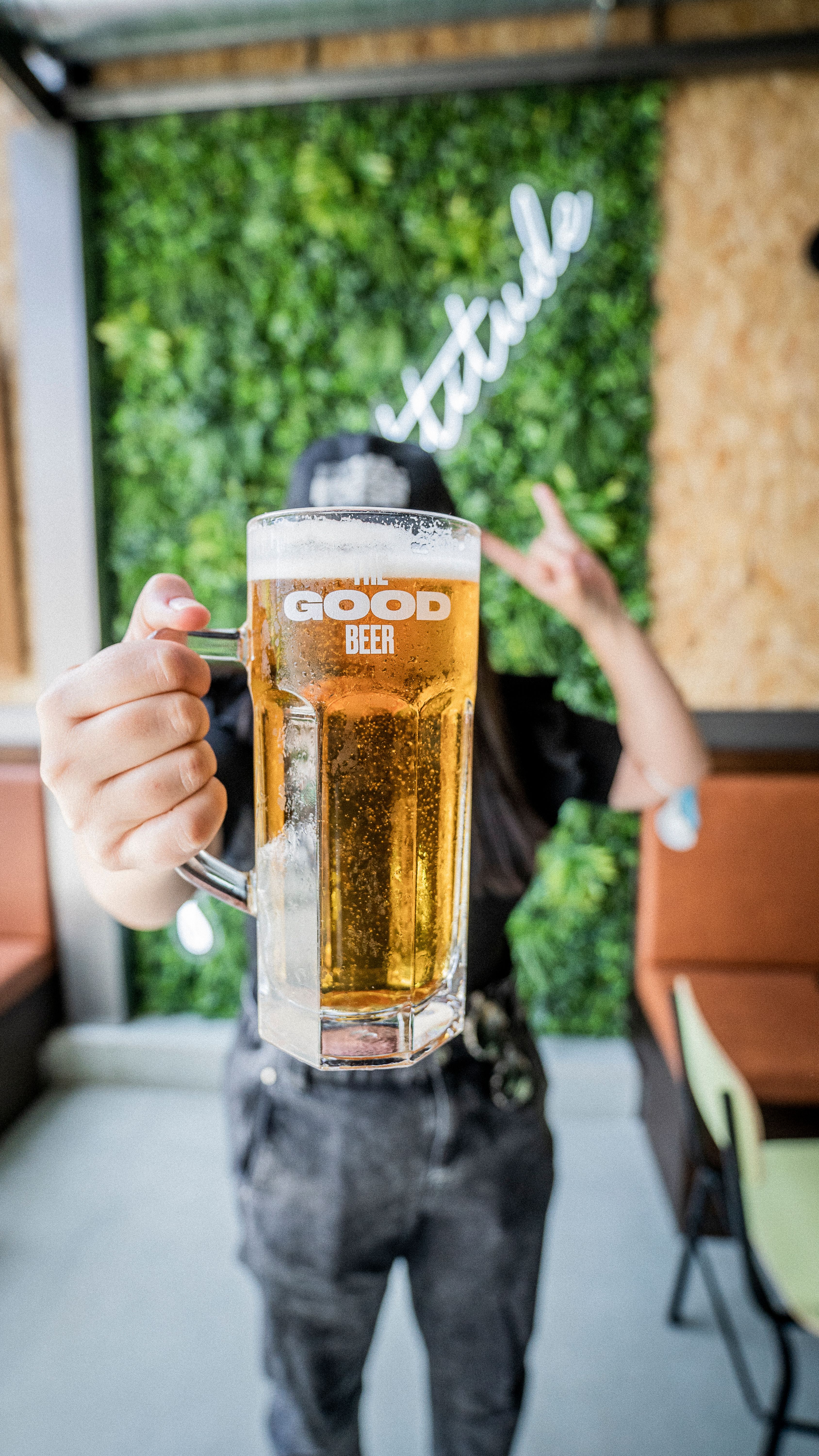 Close-up of a person holding a frosty beer mug in a stylish indoor setting.
