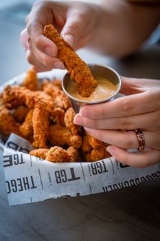 Delicious fried chicken strips being dipped into a creamy sauce, perfect for snack time.