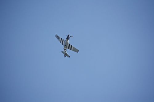 Free A vintage fighter aircraft soaring through a clear blue sky, viewed from below. Stock Photo