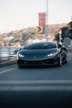 High-speed black supercar in action on a scenic road, showcasing luxury and performance.