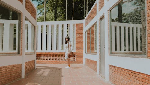 Free Woman Standing in the Middle of Brick Wall House Stock Photo