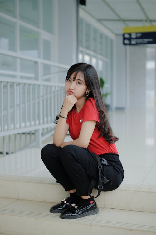 Free Woman in Red Shirt an Black Pants Sitting on Stairs  Stock Photo