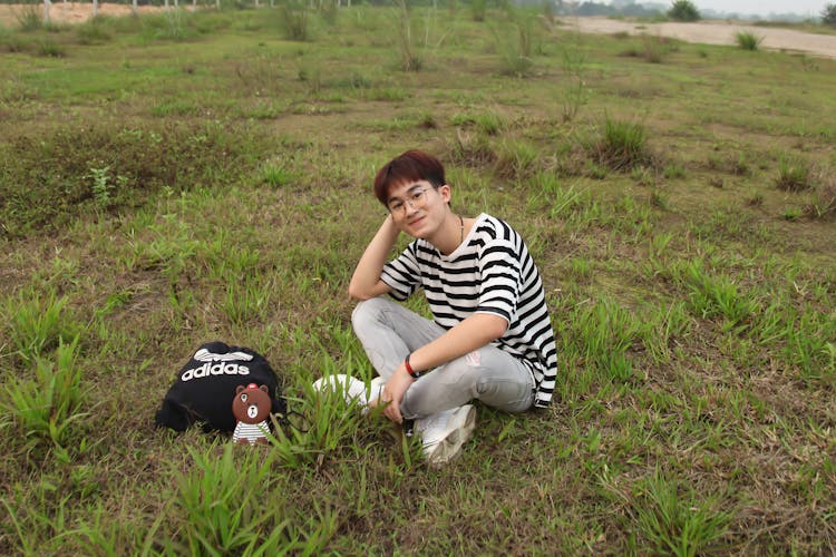 Young Man Sitting On Grass Smiling